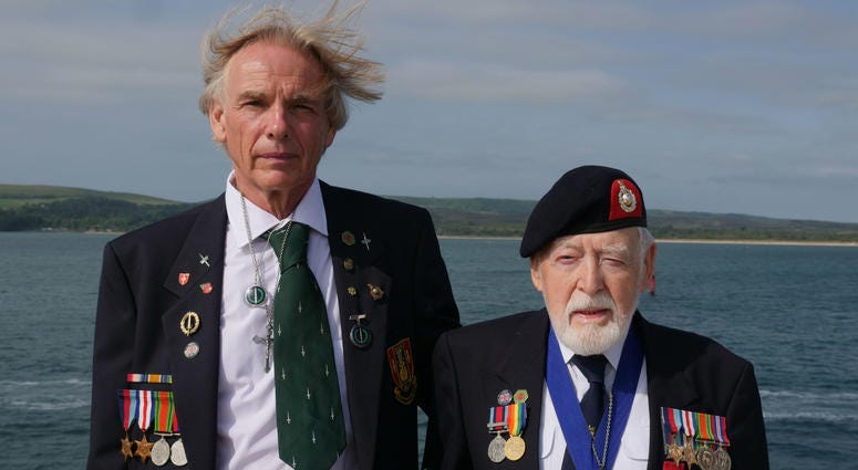 Former Royal Marine Les Budding, right, stands with Philip Collins, 62, who is the son of the late F.E. Collins of 45 Commando, who fought alongside Budding on D-Day, as they pose for a photo aboard the MV Boudicca ship. Former Royal Marine Les Budding, right, stands with Philip Collins, 62, who is the son of the late F.E. Collins of 45 Commando, who fought alongside Budding on D-Day, as they pose for a photo aboard the MV Boudicca ship.