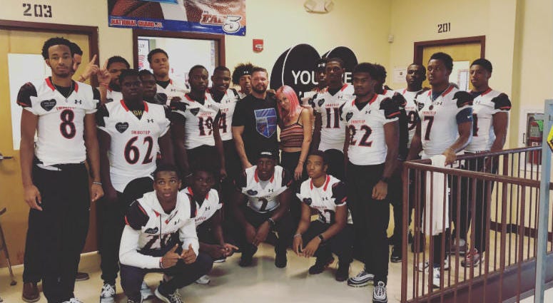 Philly street artist Amberella poses with the Imhotep Institute Charter football team. Imhotep Institute Charter football team