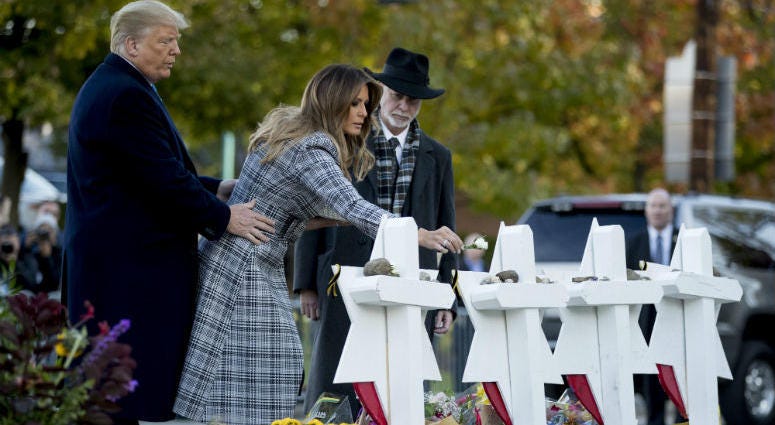 First lady Melania Trump, accompanied by President Donald Trump, and Tree of Life Rabbi Jeffrey Myers, right, puts down a white flower at a memorial for those killed at the Tree of Life Synagogue in Pittsburgh, Tuesday, Oct. 30, 2018.