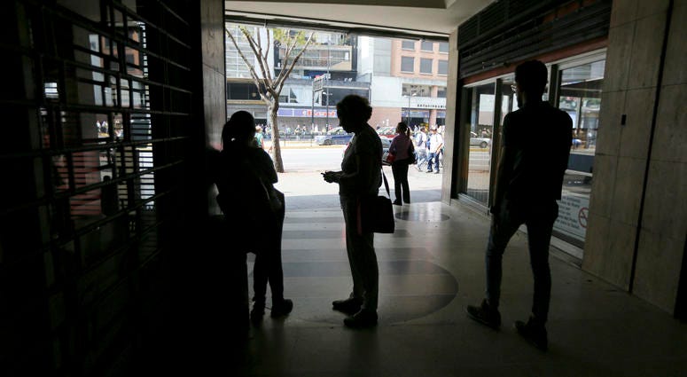 People wait inside a darkened office building during a power outage in Caracas, Venezuela, Monday, March 25, 2019. People wait inside a darkened office building during a power outage in Caracas, Venezuela, Monday, March 25, 2019.
