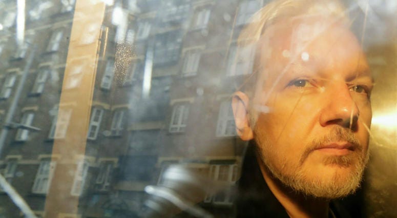 In this Wednesday May 1, 2019 file photo, buildings are reflected in the window as WikiLeaks founder Julian Assange is taken from court, where he appeared on charges of jumping British bail seven years ago, in London. In this Wednesday May 1, 2019 file photo, buildings are reflected in the window as WikiLeaks founder Julian Assange is taken from court, where he appeared on charges of jumping British bail seven years ago, in London.