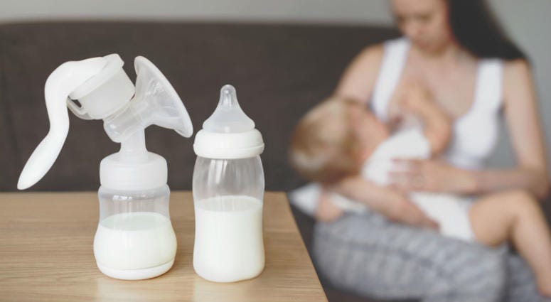 Bottle and breast pump with breast milk on the background of mother holding in her hands and breastfeeding baby Bottle and breast pump with breast milk on the background of mother holding in her hands and breastfeeding baby
