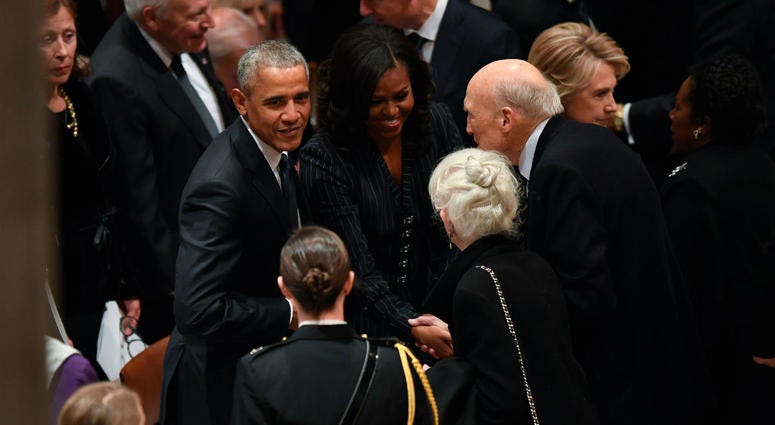 Former President Barack Obama and his wife, Michelle Obama, greet former Sen. Alan Simpson as former President George H.W. Bush before a state funeral at the Washington National Cathedral in Washington, Dec. 5, 2018. Former President Barack Obama and his wife, Michelle Obama, greet former Sen. Alan Simpson as former President George H.W. Bush before a state funeral at the Washington National Cathedral in Washington, Dec. 5, 2018.