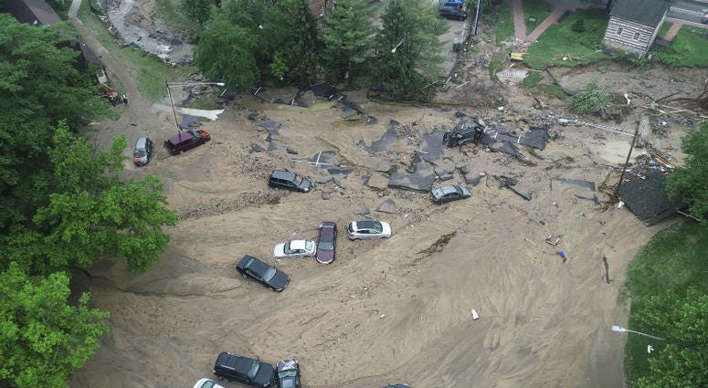 This image made from video provided by DroneBase shows vehicles swept by floodwater near the intersection of Ellicott Mills Drive and Main Street in Ellicott City, Md., Monday, May 28, 2018. flooding in Ellicott City, Md.