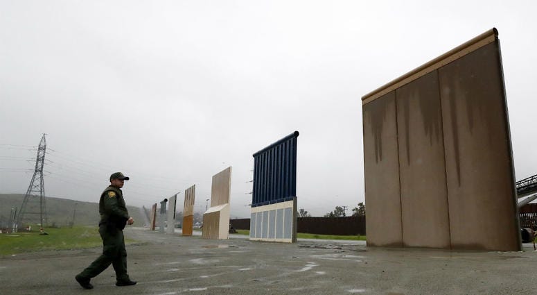 In this Feb. 5, 2019 file photo a Border Patrol agent walks towards prototypes for a border wall in San Diego. In this Feb. 5, 2019 file photo a Border Patrol agent walks towards prototypes for a border wall in San Diego.