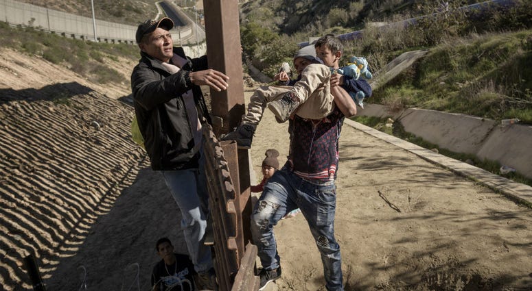 In this Saturday, Dec. 29, 2018, file photo, a man passes a Mexican migrant baby to her mother after they jump the border fence to get to the U.S. side to San Diego, from Tijuana, Mexico. In this Saturday, Dec. 29, 2018, file photo, a man passes a Mexican migrant baby to her mother after they jump the border fence to get to the U.S. side to San Diego, from Tijuana, Mexico.