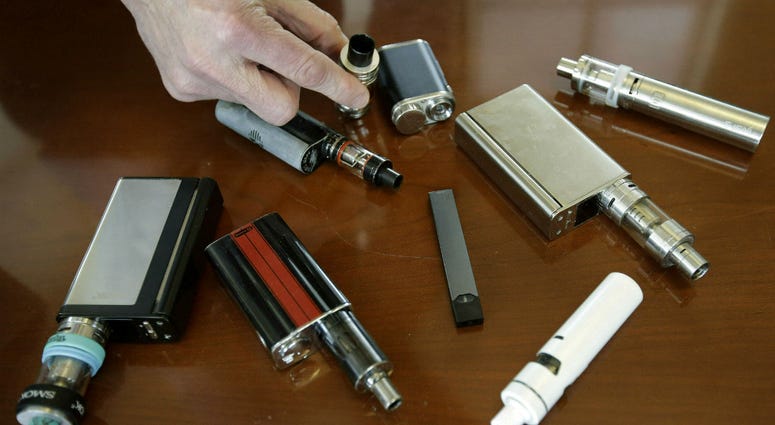 In this April 10, 2018, file photo, a high school principal displays vaping devices that were confiscated from students in such places as restrooms or hallways at the school in Massachusetts. In this April 10, 2018, file photo, a high school principal displays vaping devices that were confiscated from students in such places as restrooms or hallways at the school in Massachusetts.
