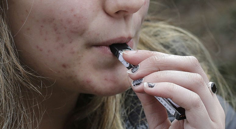 In this April 11, 2018 file photo, a high school student uses a vaping device near a school campus in Cambridge, Mass. In this April 11, 2018 file photo, a high school student uses a vaping device near a school campus in Cambridge, Mass.