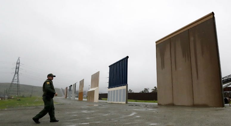 In this Feb. 5, 2019 file photo a Border Patrol agent walks towards prototypes for a border wall in San Diego. In this Feb. 5, 2019 file photo a Border Patrol agent walks towards prototypes for a border wall in San Diego.