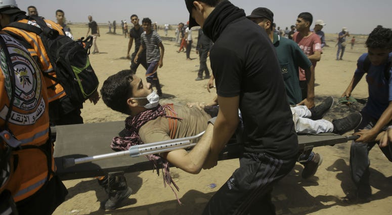 Palestinian medics and protesters evacuate a wounded youth near the Gaza Strip's border with Israel during a protest east of Khan Younis, in the Gaza Strip, Friday, June 8, 2018. Palestinian medics and protesters evacuate a wounded youth