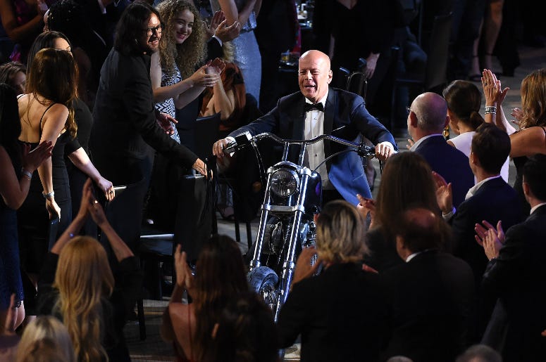 LOS ANGELES - JULY 14: Bruce Willis enters on a motorcycle at the "Comedy Central Roast of Bruce Willis" at the Hollywood Palladium on July 14, 2018 in Los Angeles, California. LOS ANGELES - JULY 14: Bruce Willis enters on a motorcycle at the "Comedy Central Roast of Bruce Willis" at the Hollywood Palladium on July 14, 2018 in Los Angeles, California.