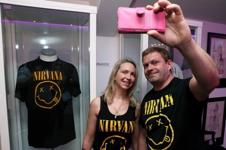 Nirvana fans Tanya and Dave Deegan, from Dublin, take a picture alongside Kurt Cobain's Nirvana smiley face t-shirt at the opening of the 'Growing Up Kurt' exhibition on the life of the Nirvana frontman, at the museum of Style Icons in Newbridge, Ireland. Nirvana fans Tanya and Dave Deegan, from Dublin, take a picture alongside Kurt Cobain's Nirvana smiley face t-shirt at the opening of the 'Growing Up Kurt' exhibition on the life of the Nirvana frontman, at the museum of Style Icons in Newbridge, Ireland.