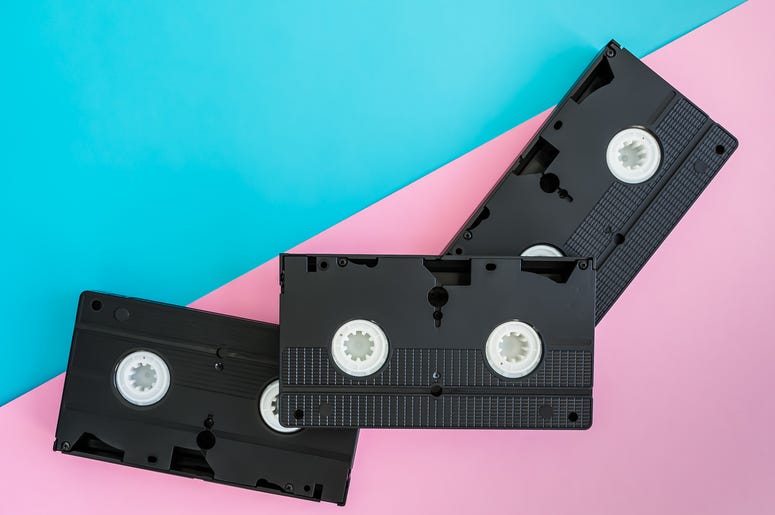 3 black VHS video tapes lying diagonally on a bright pink and blue background. 3 black VHS video tapes lying diagonally on a bright pink and blue background.