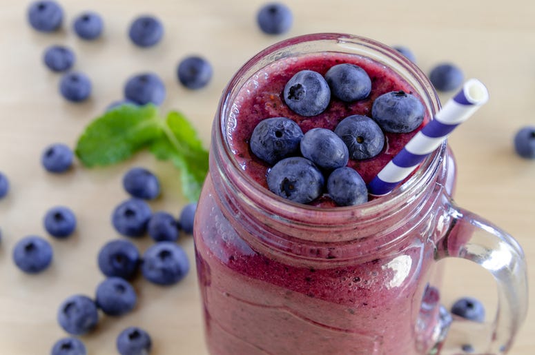 Blueberry and Blackberry smoothie shakes. Berries, table Mason jar filled with blueberry and blackberry fresh fruit smoothie sitting on counter with bowl of blueberries.