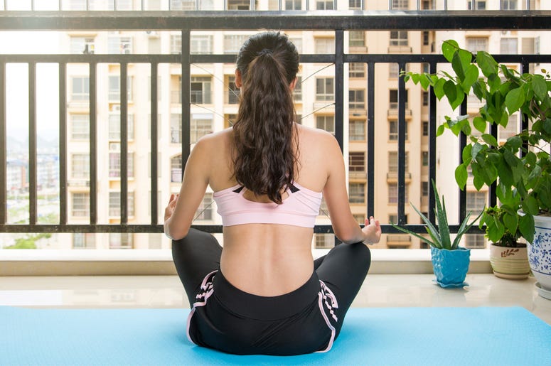 Girl meditating at the balcony on a yoga mat. Home workout Girl meditating at the balcony on a yoga mat. Home workout