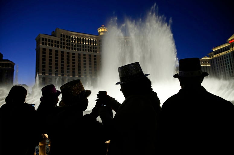 AP18356048162905 In this Dec. 31, 2015, file photo, people watch the fountains at the Bellagio while wearing paper hats to celebrate New Years Eve in Las Vegas. Las Vegas will usher in 2019 trying to outdo itself with performances by Lady Gaga, Gwen Stefani, Bruno Mars an
