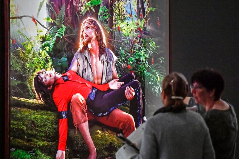 AP19080419247507 Visitors talk about the picture 'American Jesus: Hold me, carry me boldly' from US artist David LaChapelle at a preview of the exhibition 'Michael Jackson: On The Wall' at the Bundeskunsthalle museum in Bonn, Germany, Thursday, March 21, 2019. The exhibit