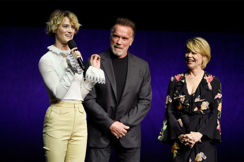 AP19094703043122 Mackenzie Davis, left, a cast member in the upcoming film "Terminator: Dark Fate," talks about the film as fellow cast members Arnold Schwarzenegger, center, and Linda Hamilton look on during the Paramount Pictures presentation at CinemaCon 2019, the offi