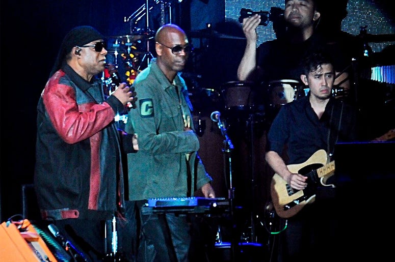 AP19238076975193 Musician Stevie Wonder, left, is escorted by comedian Dave Chappelle during the "Gem City Shine," event in the Oregon District in Dayton, Ohio, Sunday, Aug. 25, 2019. (Marshall Gorby/Dayton Daily News via AP)