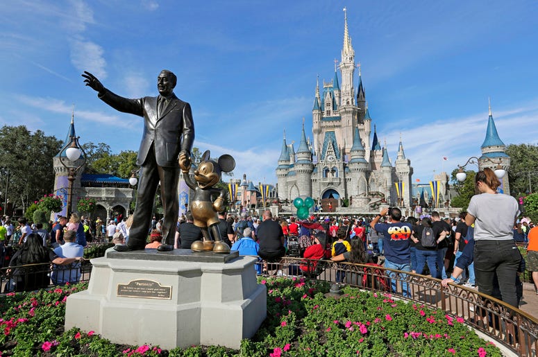 AP19309656956430 In this Jan. 9, 2019 file photo, guests watch a show near a statue of Walt Disney and Mickey Mouse in front of the Cinderella Castle at the Magic Kingdom at Walt Disney World in Lake Buena Vista, Florida. (AP Photo/John Raoux, File)