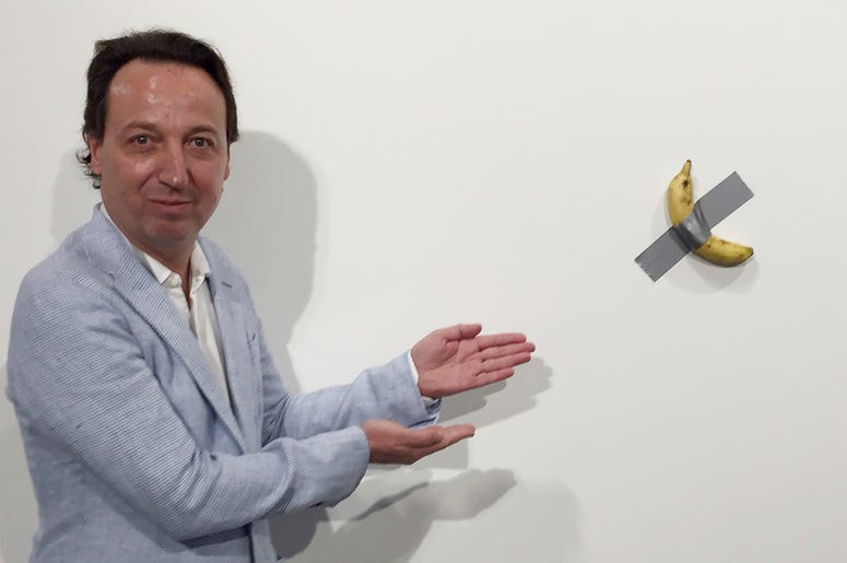 AP19346591136029 In this Dec. 4, 2019 photo, gallery owner Emmanuel Perrotin poses next to Italian artist Maurizio Cattlelan's "Comedian" at the Art Basel exhibition in Miami Beach, Florida. (Siobhan Morrissey via AP)