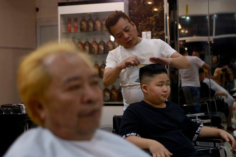 Le Phuc Hai, 66, left, and To Gia Huy, 9, have Trump and Kim haircuts in Hanoi, Vietnam, on Tuesday, Feb. 19, 2019. U.S. President Donald Trump and North Korean leader Kim Jong Un have become the latest style icons in Hanoi, a week before their second sum
