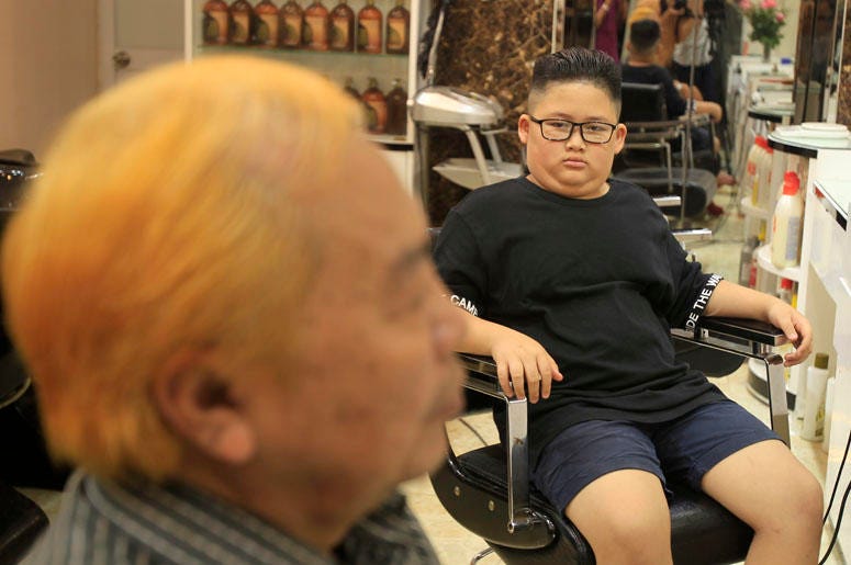 Le Phuc Hai, 66, left, and To Gia Huy, 9, have Trump and Kim haircuts in Hanoi, Vietnam, on Tuesday, Feb. 19, 2019. U.S. President Donald Trump and North Korean leader Kim Jong Un have become the latest style icons in Hanoi, a week before their second sum