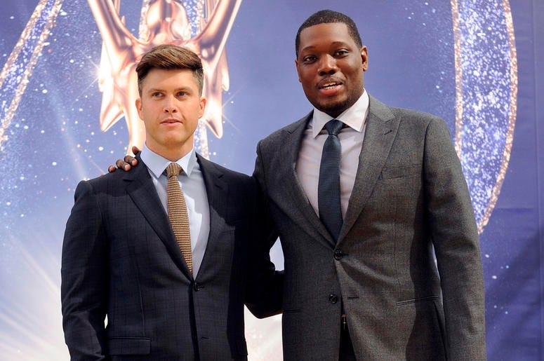 AP18256657431047 Colin Jost, left, and Michael Che, co-hosts for the 70th Emmy Awards, speak to the media before rolling out the gold carpet outside the Microsoft Theatre, Thursday, Sept. 13, 2018, in Los Angeles. The awards will be held on Monday. (Photo by Chris Pizzell