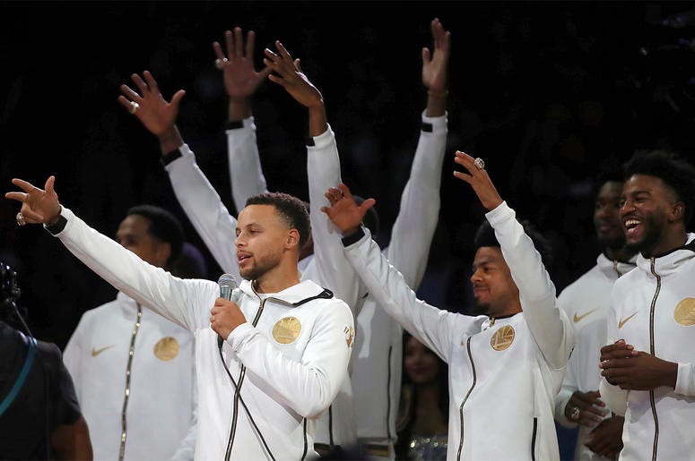 AP18290127159063 Golden State Warriors' Stephen Curry, left, speaks to fans during an awards ceremony to recognize the team's NBA championship prior to a basketball game against the Oklahoma City Thunder, Tuesday, Oct. 16, 2018, in Oakland, Calif. (AP Photo/Ben Margot)