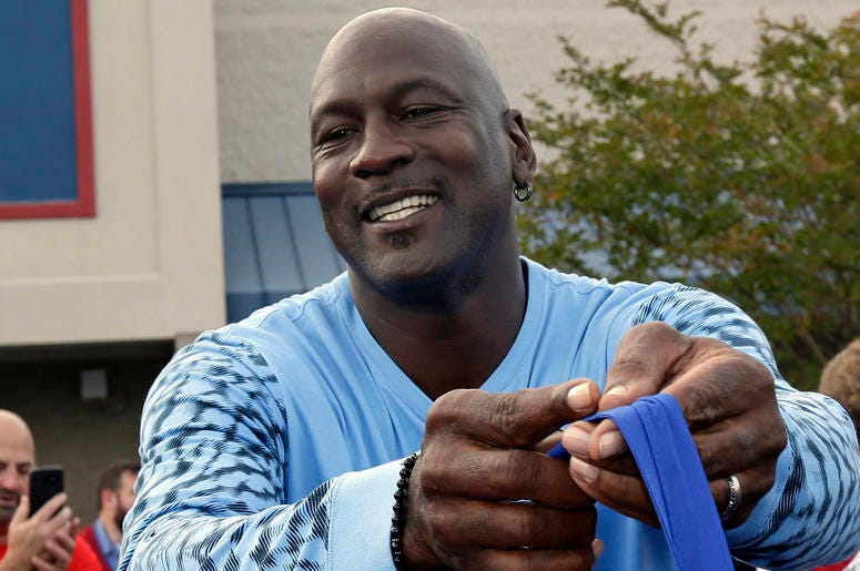 AP18324797423526 Charlotte Hornets owner Michael Jordan greets people and hands out food for Thanksgiving to members of the community in Wilmington, N.C., Tuesday, Nov. 20, 2018. (AP Photo/Gerry Broome)