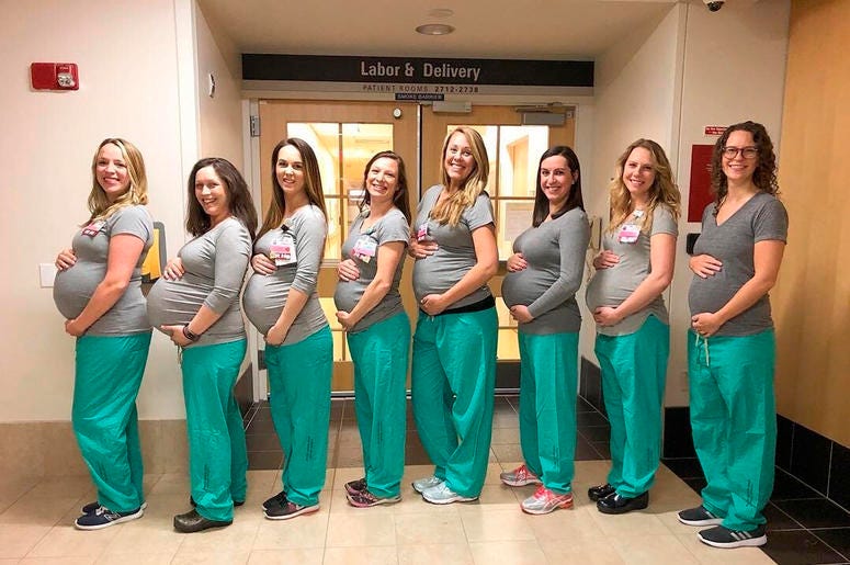 AP19084719057503 In this March 23, 2019 photo, eight labor and delivery nurses at Maine Medical Center hold up cards with their due dates in Portland, Maine. The pictured nurses, from left to right, are Erin Grenier, Rachel Stellmach, Brittney Verville, Lonnie Souci, Aman