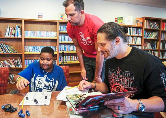 AP19009154182822 Hospital patient Yaheim Young, 15, of Penn Hills, Pa., left, Nick Manganiello, center, and his brother, Mt. Lebanon native and actor Joe Manganiello, right, count dice as they create their Dungeons and Dragons characters at UPMC Children's Hospital of Pit