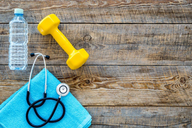 Health & Fitness Sport and health. Fitness. Dumbbells and stethoscope on wooden background top view copyspace