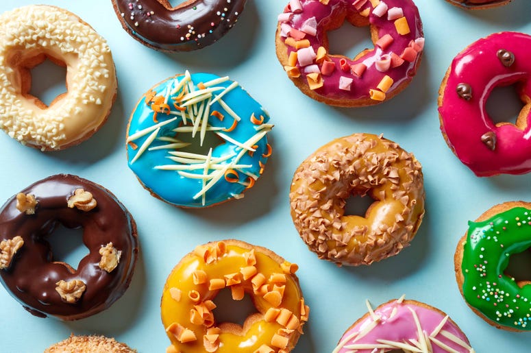 A plate with donuts in a variety of colors and flavors