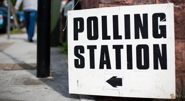 A uk Polling station sign hooked on a wall on a street - stock photo Directions to a polling station for a UK general election, European election or local election. Shallow depth of field. GettyImages-149075978.jpg