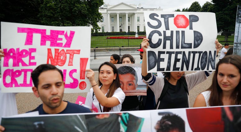 People hold up signs and photographs during a demonstration opposed to the White House policy that separated more than 2,300 children from their parents over the past several weeks in front of the White House in Washington, Thursday, June 21, 2018. (AP Ph