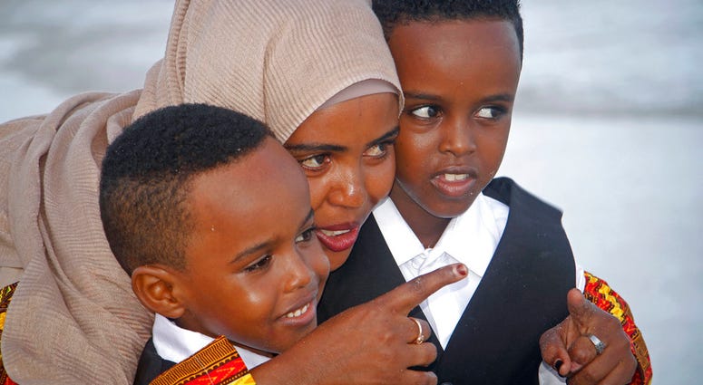 Maryan Abdullahi, who had been hoping to go to neighboring Ethiopia where their U.S. travel plans were to have been processed, walks with her two sons on the beach in Mogadishu, Somalia, Wednesday, June 27, 2018.