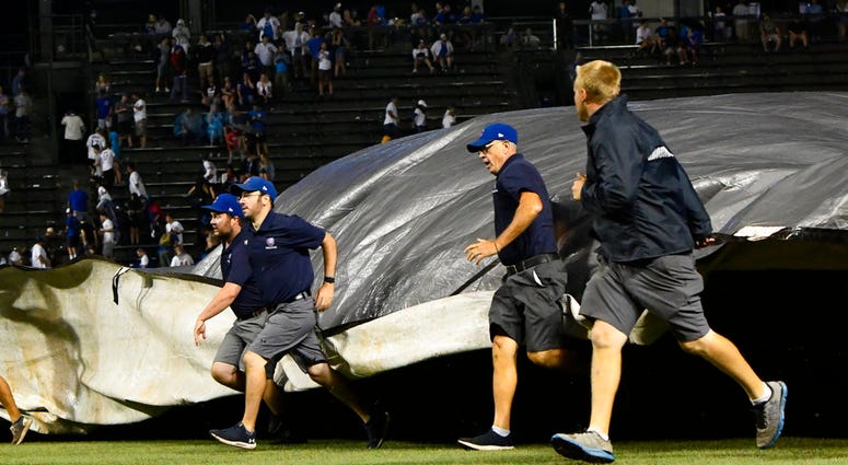 Chicago Cubs' ground crew lay down the tarp due to a storm during the 10th inning of a baseball game against the New York Mets on Tuesday, Aug. 28, 2018, in Chicago.