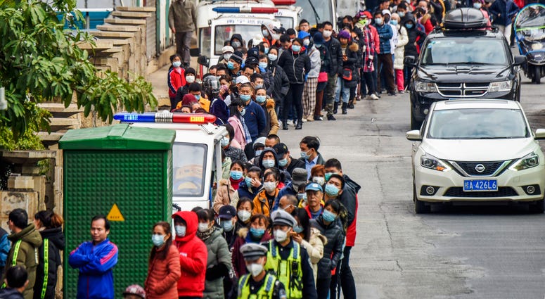 In this Jan. 29, 2020, file photo, people line up to buy face masks from a medical supply company in Nanning in southern China's Guangxi Zhuang Autonomous Region