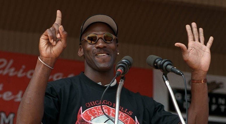 Chicago Bulls' Michael Jordan holds up six fingers, one for each championship, as he addresses the crowd gathered for the Bulls' championship rally at Grant Park in Chicago on June 16, 1998.