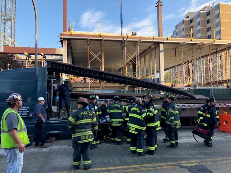 Firefighters respond to a construction site where a steel beam fell from a crane Monday morning, killing one worker and critically injuring another.
