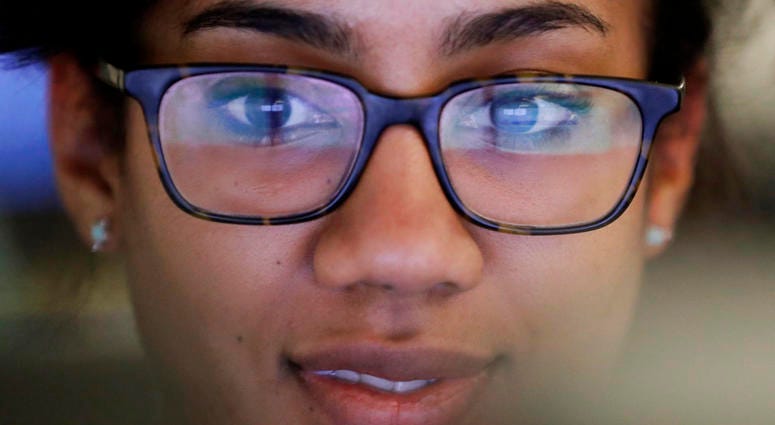 In this Wednesday, April 25, 2018 photo, Kim Smith works on her computer at University of Chicago-Crime Lab in Chicago. An unusual partnership involving the five major pro sports teams in Chicago is helping fight youth violence in the city. The Chicago Sp