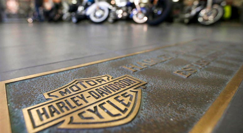 rows of motorcycles are behind a bronze plate with corporate information on the showroom floor at a Harley-Davidson dealership in Glenshaw, Pa.