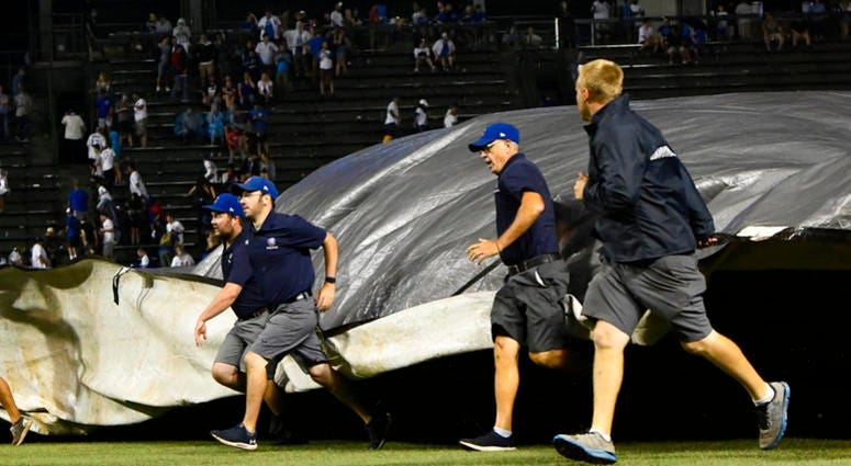 Chicago Cubs' ground crew lay down the tarp due to a storm during the 10th inning of a baseball game against the New York Mets on Tuesday, Aug. 28, 2018, in Chicago.