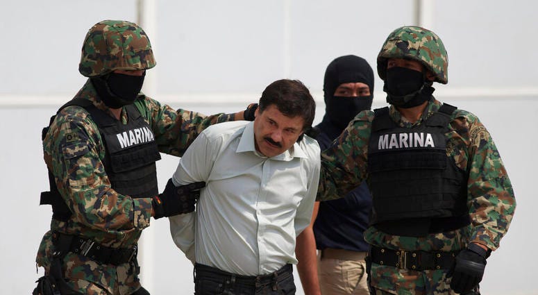 In this Saturday, Feb. 22, 2014 file photo, Joaquin "El Chapo" Guzman, center, is escorted to a helicopter in handcuffs by Mexican navy marines at a hanger in Mexico City, after he was captured overnight in the beach resort town of Mazatlan.