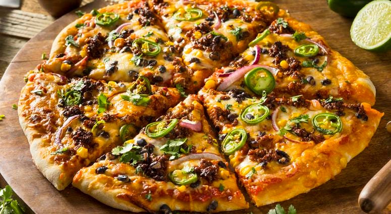A whole pizza with sausage, olives and peppers