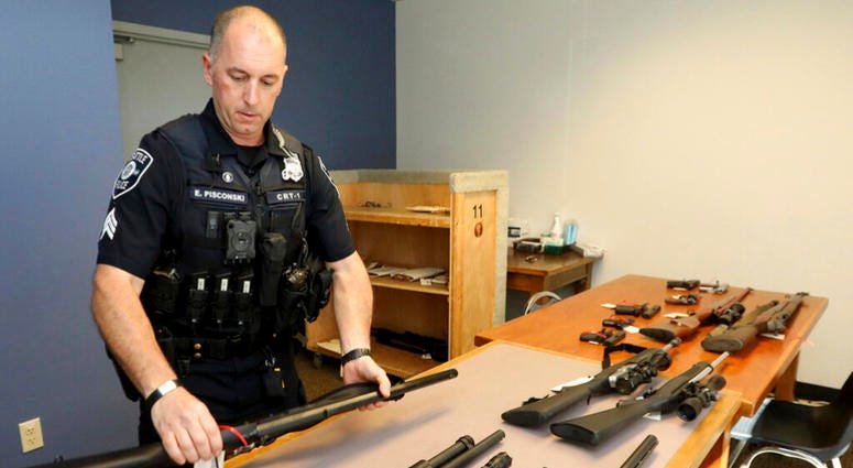 In this May 23, 2018, photo, Seattle Police Crisis Response Team Sgt. Eric Pisconski displays guns seized from people deemed to be a danger to themselves or others. In this May 23, 2018, photo, Seattle Police Crisis Response Team Sgt. Eric Pisconski displays guns seized from people deemed to be a danger to themselves or others.