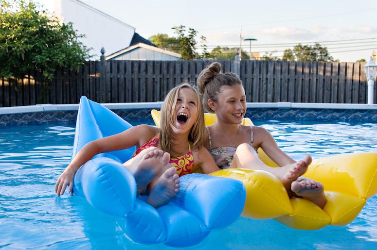two young children floating in a backyard pool two young children floating in a backyard pool