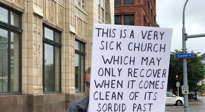 Protester with sign outside Diocese of Buffalo. September 10, 2018 (WBEN Photo/Mike Baggerman)