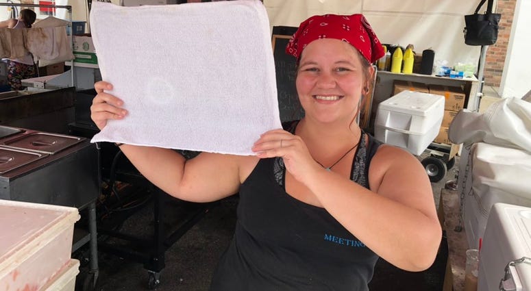 Elise Taft shows off the frozen towel she's using to keep herself cool while working at CanalFest. July 19, 2019 (WBEN Photo/Mike Baggerman)